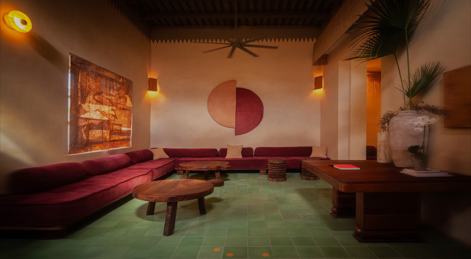 La sala — sunken red velvet banquette, jade tile floor, woven tapestry